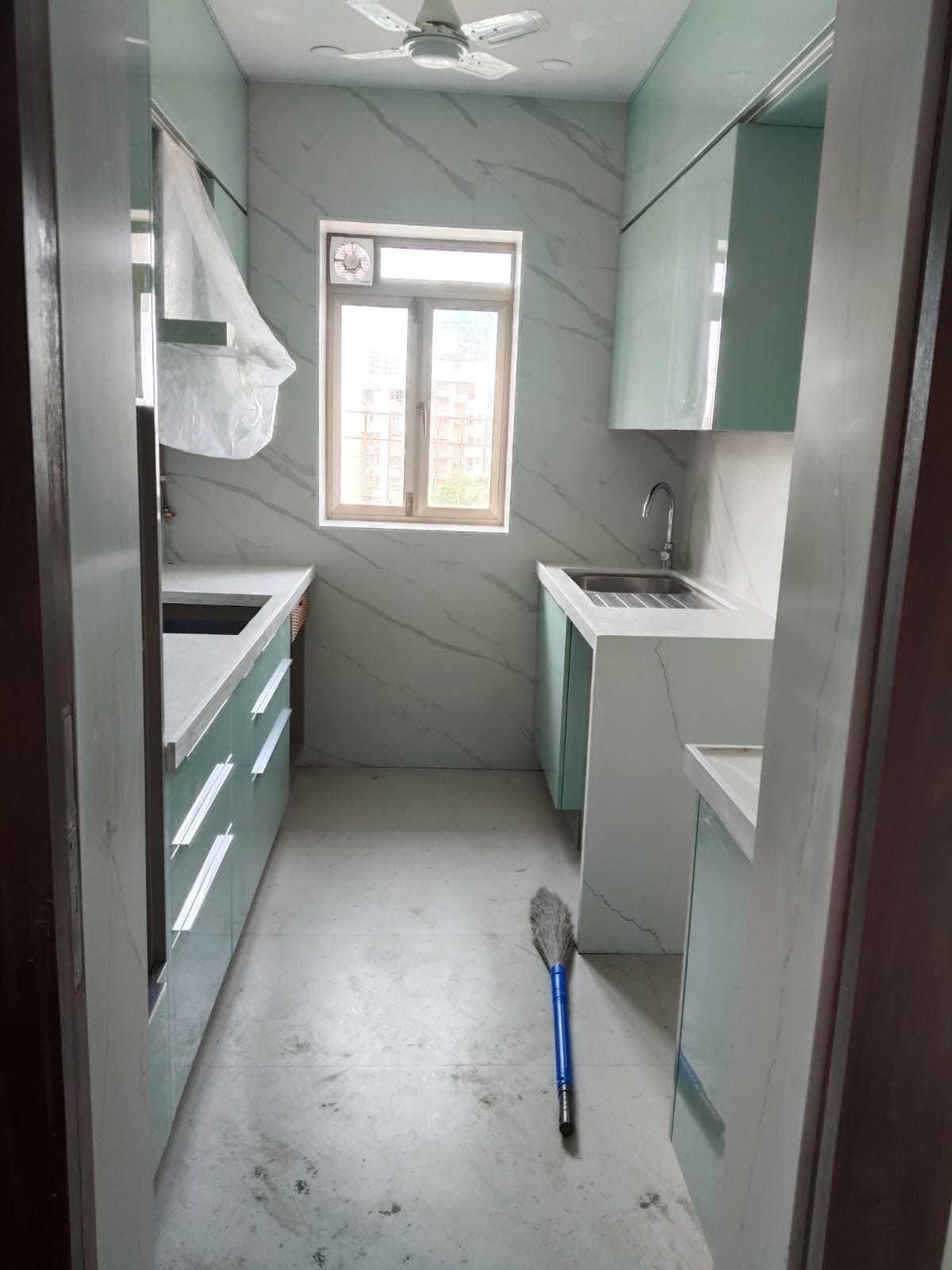 Modular kitchen renovation with marble wall cladding and mint green cabinets – Laxman Construction Mumbai